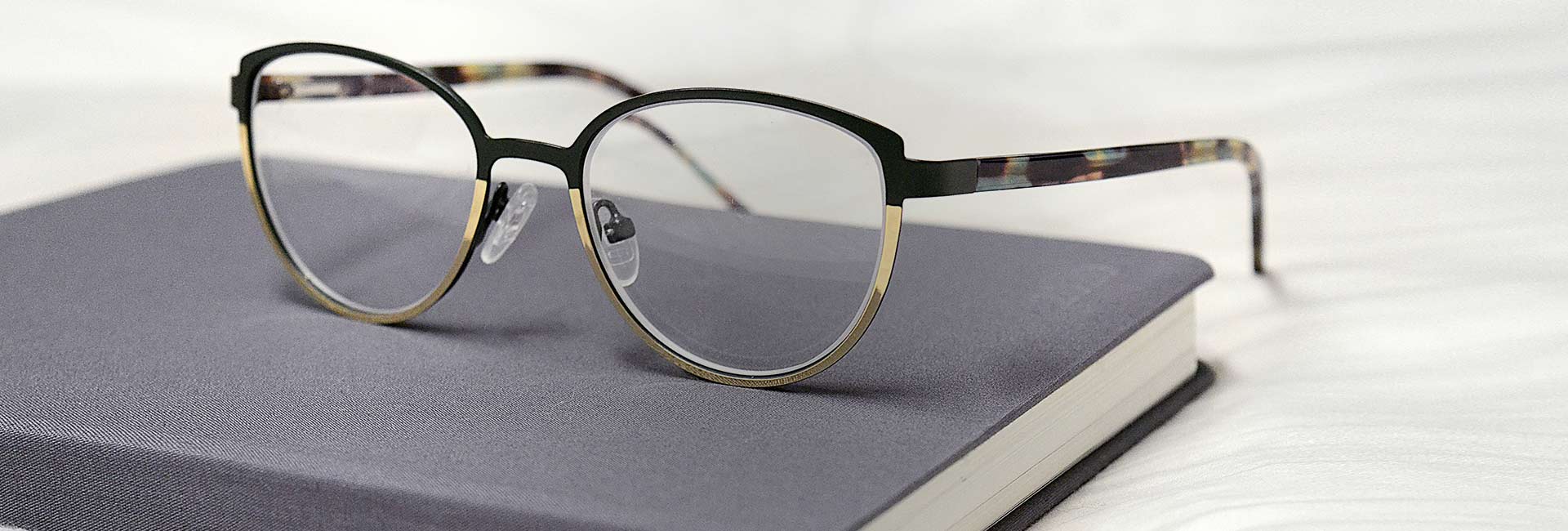 Occhiali tondi da Ottica Angelone su un libro grigio chiuso, poggiati su una ...